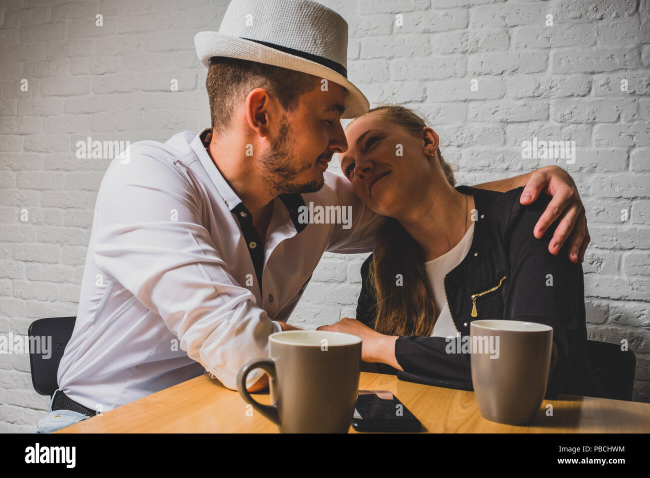 The girl and the guy in cafe, at a table, talk. The loving couple sits ...