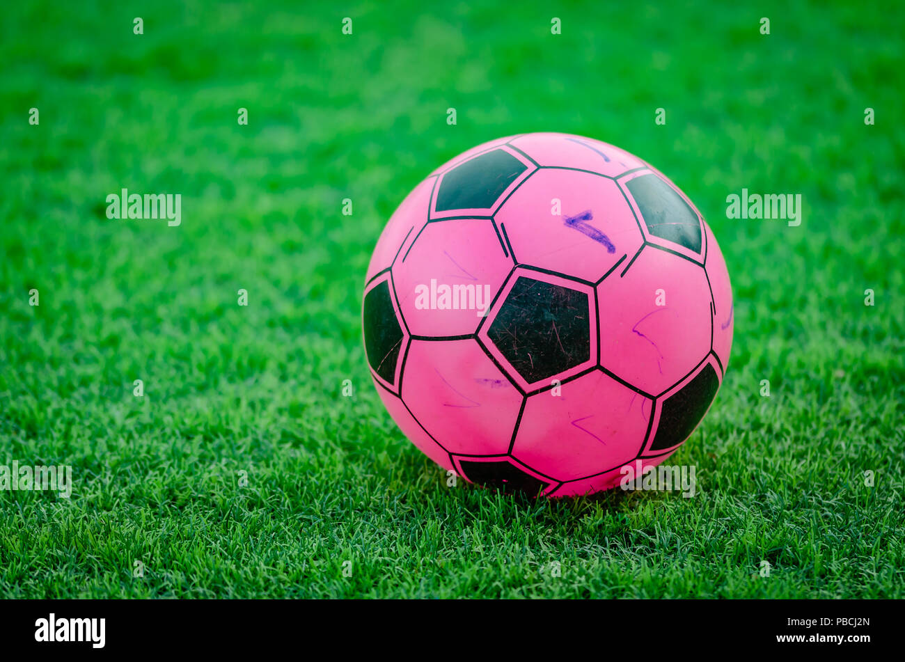 Old soccer ball with markings of children, on a football field. Stock Photo
