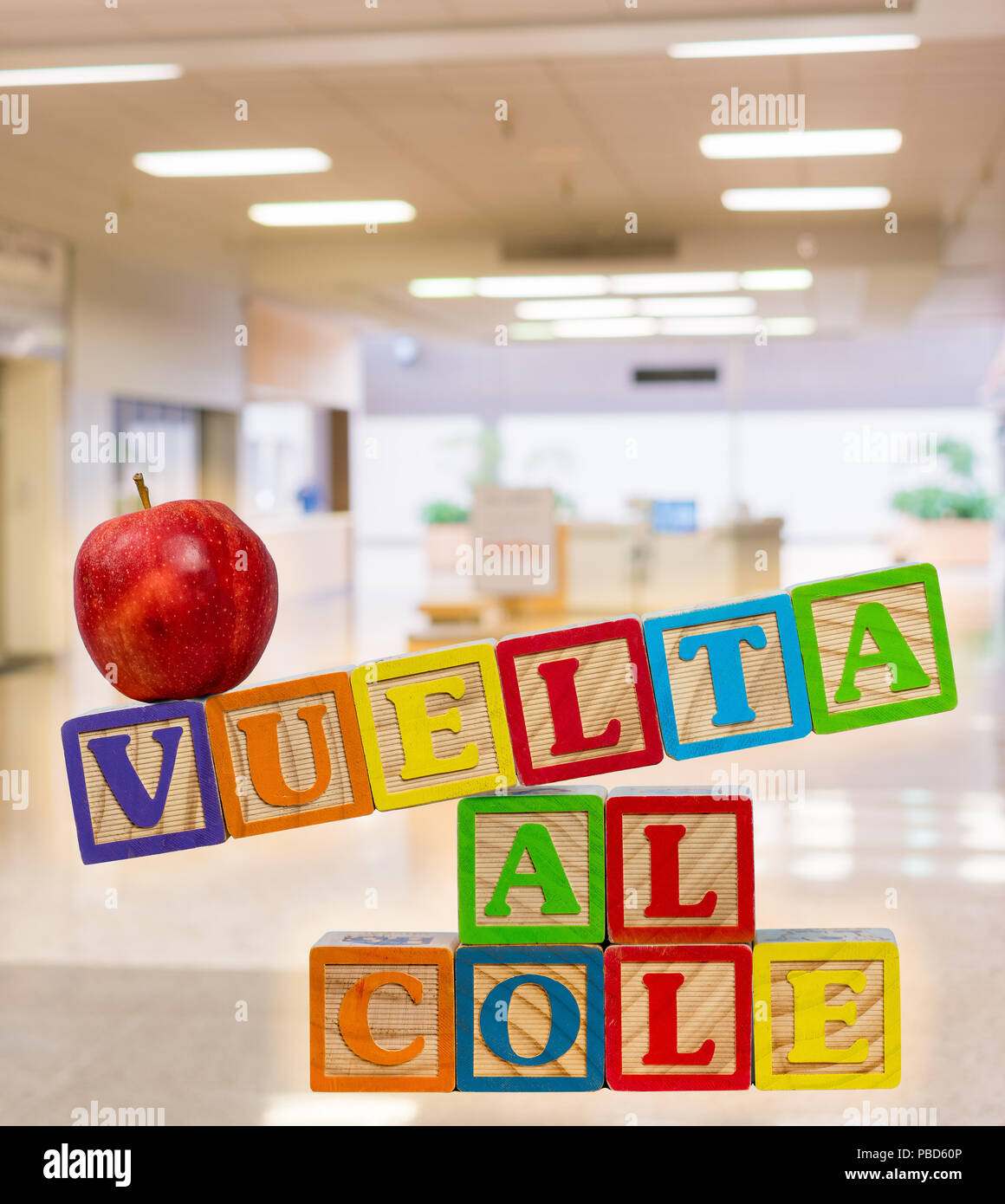 Back to School spelled out in spanish with wooden blocks with apple Stock Photo