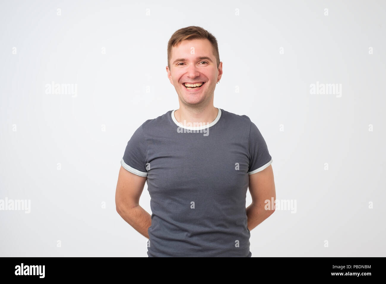 Confident young handsome man keeping arms crossed and smiling while standing against white background Stock Photo