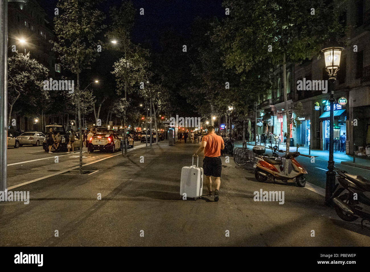 Barcelona, Catalonia, Spain. 28th July, 2018. A tourist is seen dragging his suitcase with no taxis.Taxi drivers strike indefinitely and hundreds of taxis are parked along the Gran VÃ-a de Barcelona. The taxi drivers plan to keep the strike until the Government of Spain approves next Friday a decree Law with the modifications claimed. Credit: Paco Freire/SOPA Images/ZUMA Wire/Alamy Live News Stock Photo