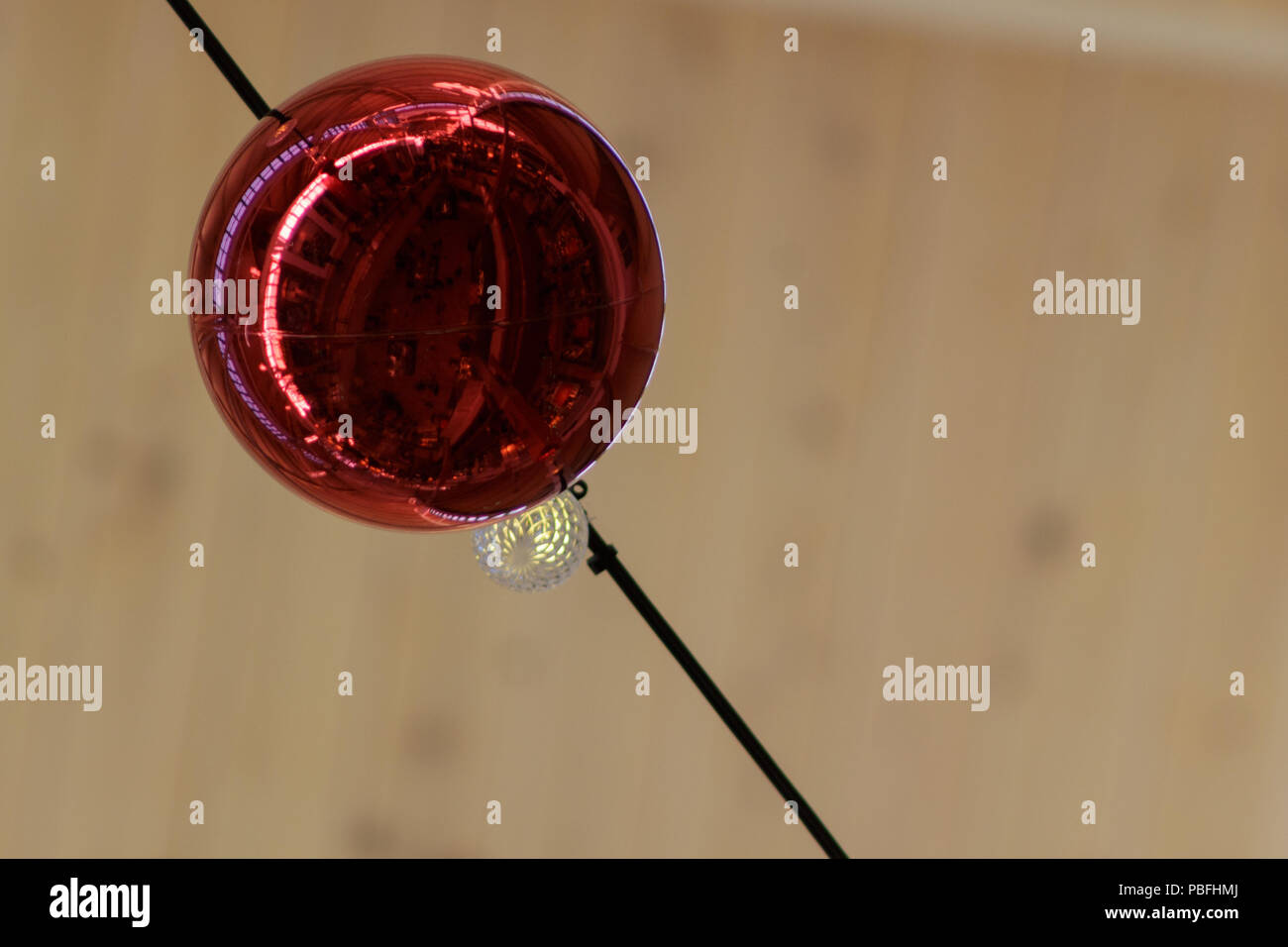 Red ornamental ball reflecting the mall from underneath at Christmastime. Stock Photo
