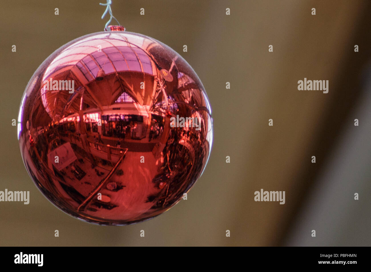 Red ornamental ball close up reflecting the mall at Christmastime. Stock Photo