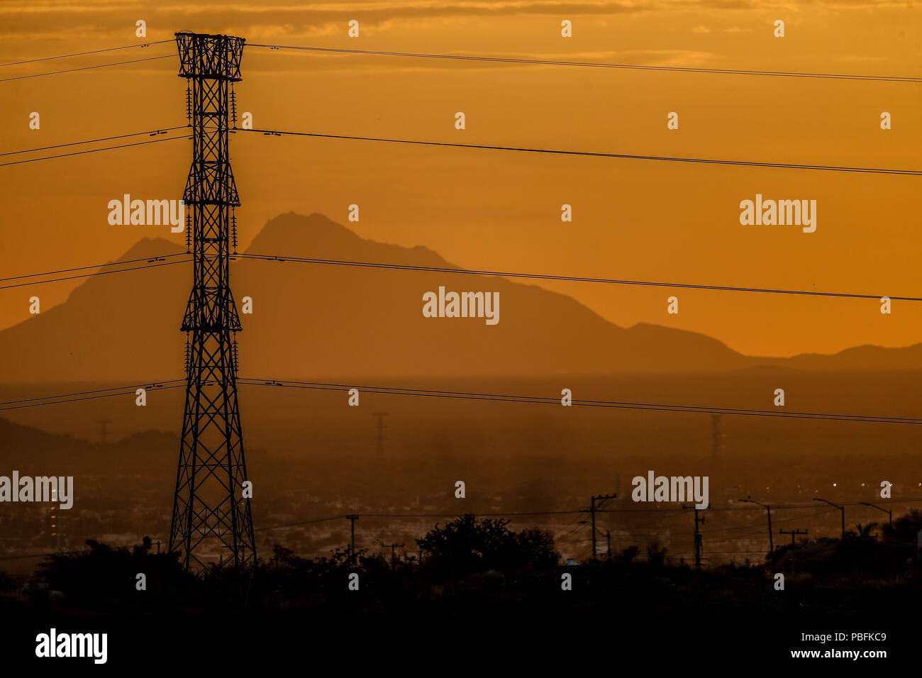 Reflection color orange and golden color by the sun hiding behind the hill of a hill. Tower and Calbes of high tension or electric current of the CFE. Stock Photo
