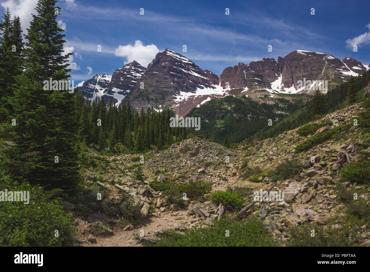 Majestic Maroon Bells peaks seen from the rugged Crater Lake Trail on a sunny day with blue sky in summer near Aspen, Colorado Stock Photo