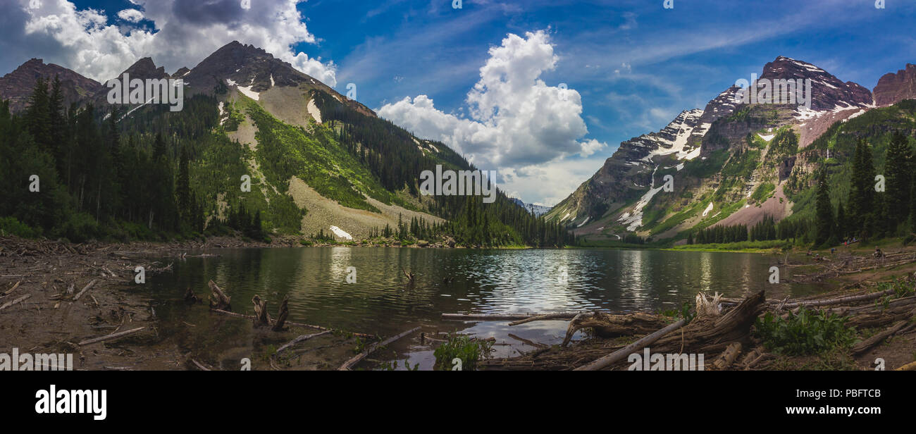 Panorama of Pyramid Peak (left), Maroon Bells (right), and Crater Lake in Snowmass Wilderness in Aspen, Colorado with a blue sky and clouds in summer Stock Photo