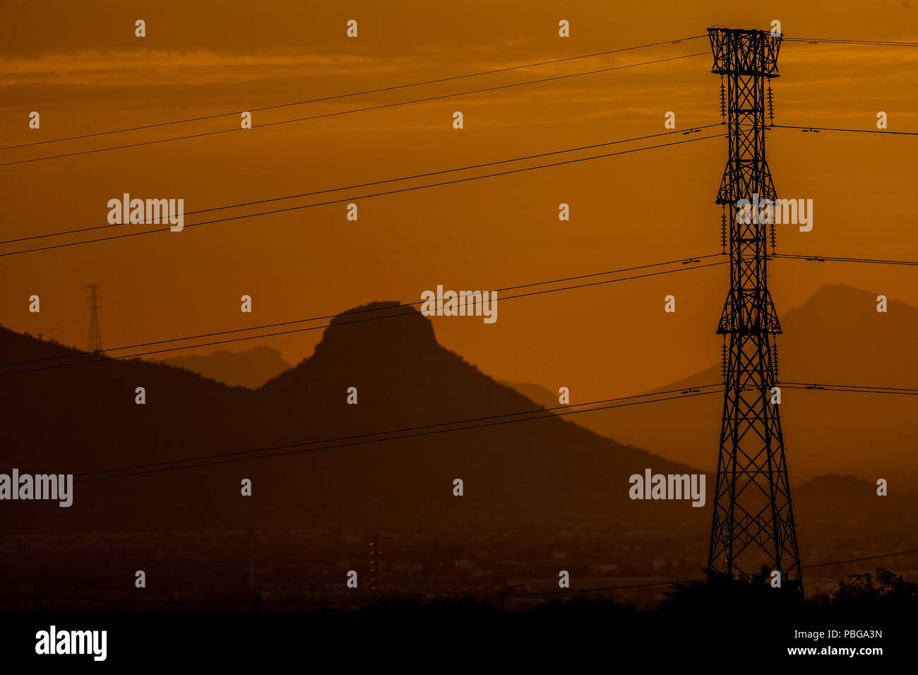 Reflection color orange and golden color by the sun hiding behind the hill of a hill. Tower and Calves of high voltage or electric current of the CFE. Sunset in the west of Hermosillo, being the capital of Sonora one of the hottest in the country. High temperatures. Centigrades Twilight.  Altas temperaturas. Centigrados. Crepusculo.  (Photo: Luis Gutiérrez / NortePhoto.com) Stock Photo