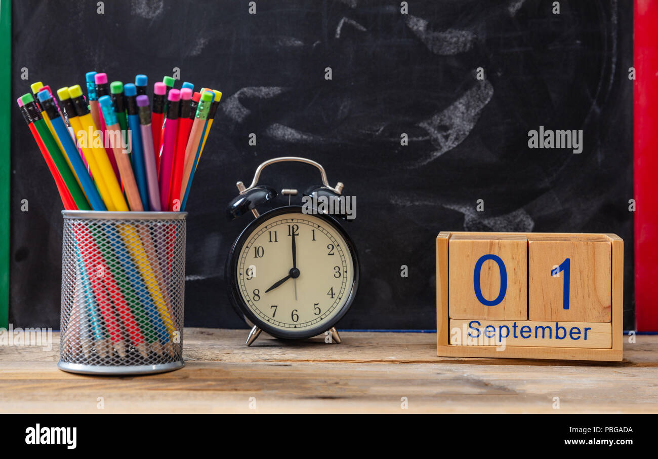 Time for school. September 1st date, alarm clock and colorful pencils on blackboard background Stock Photo