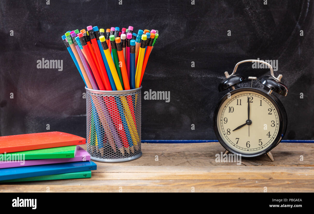 Time for school. School supplies and alarm clock on wooden desk