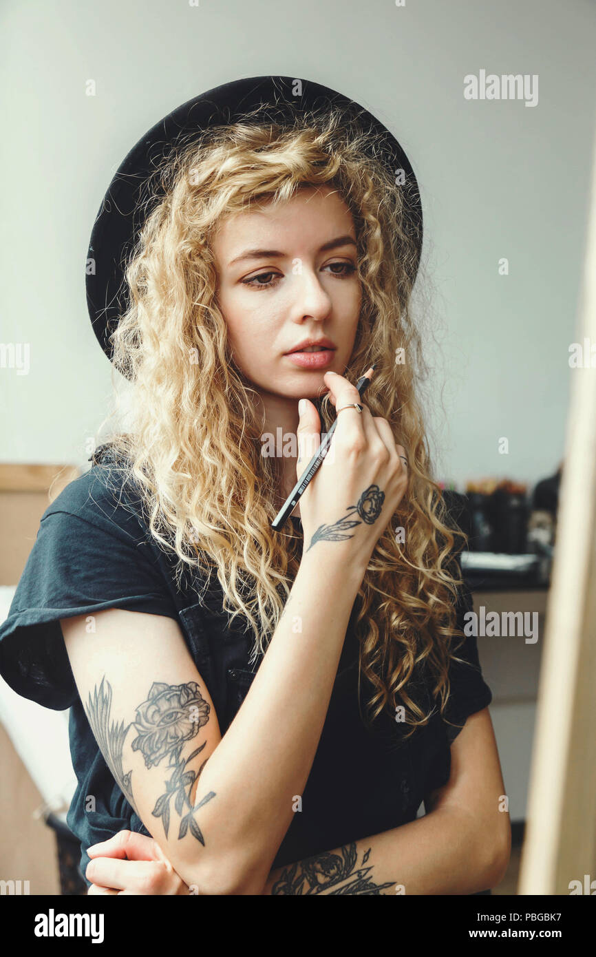 Curly Blonde Girl In Glorious Black Hat Sitting With Pencil Behind