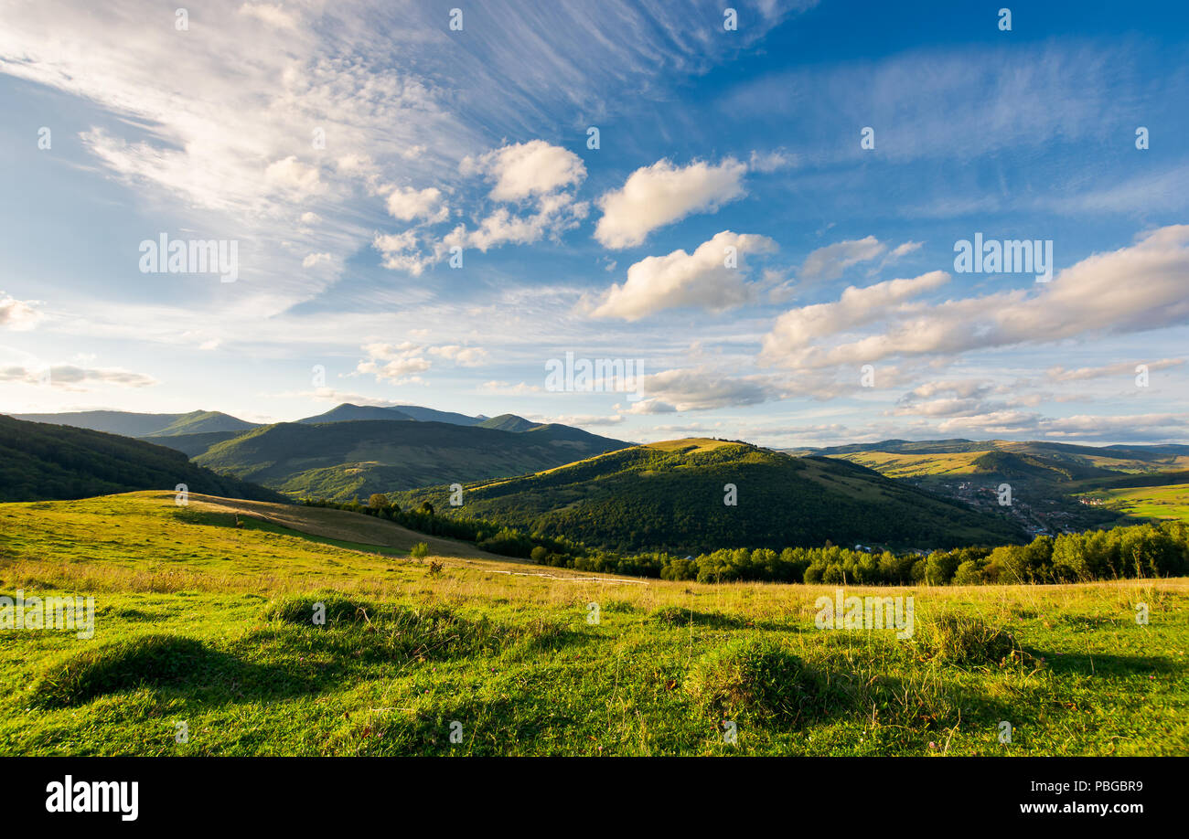 beautiful landscape in afternoon. gorgeous blue sky with golden clouds over the mighty mountain ridge in the distance. magical moment of nature Stock Photo