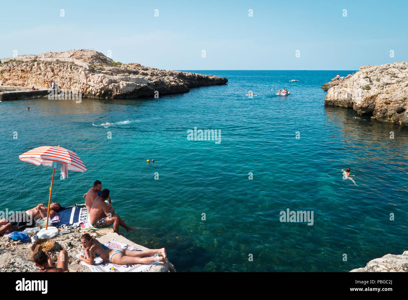 Polignano,Italy,07/16/2018; unrecognizable people one sunny day to the beach of Polignano,who are enjoying relax in the bay. Stock Photo