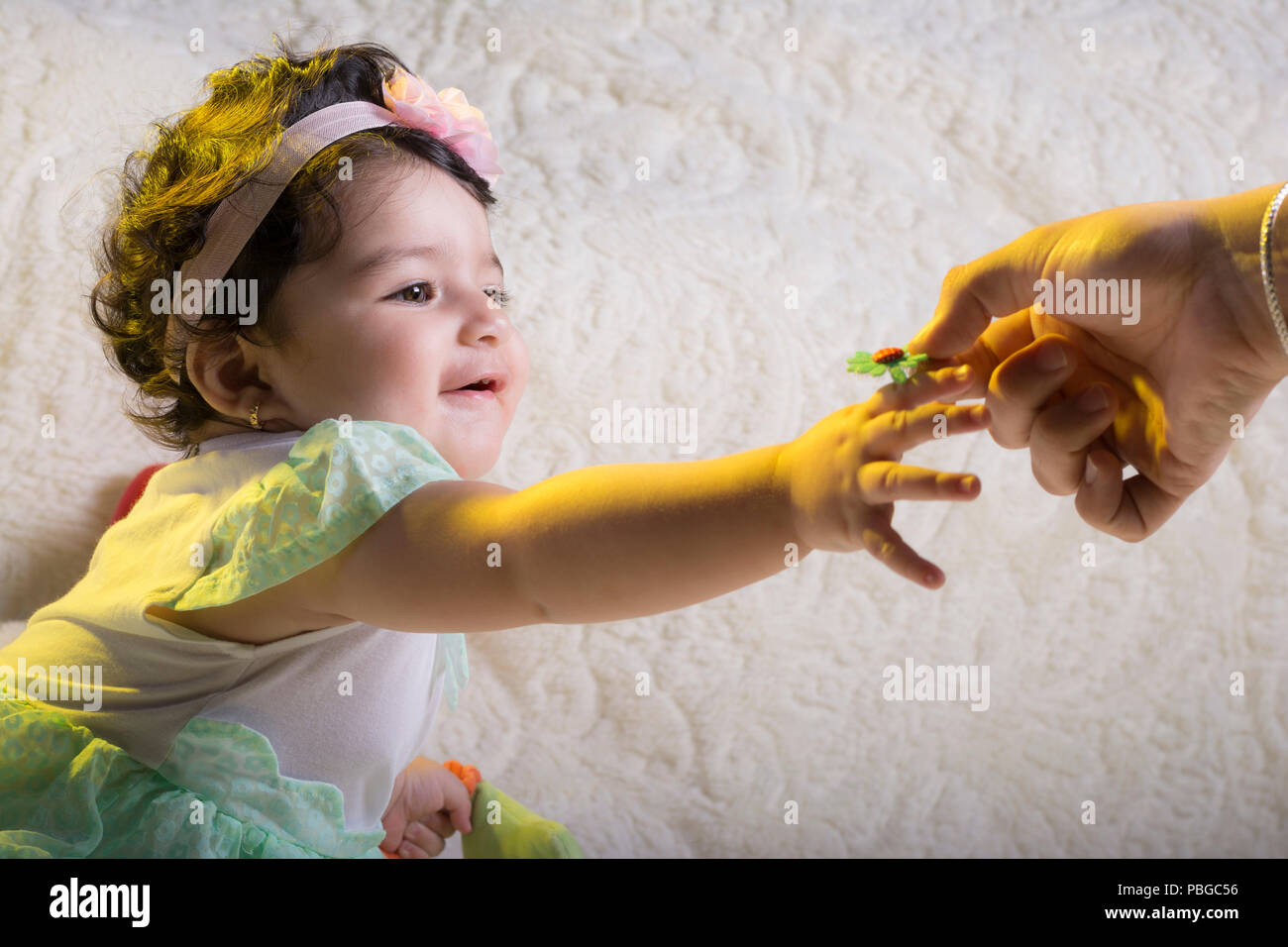 Mother Give A Little Plastic Flower To Little Girl In Front Of White 