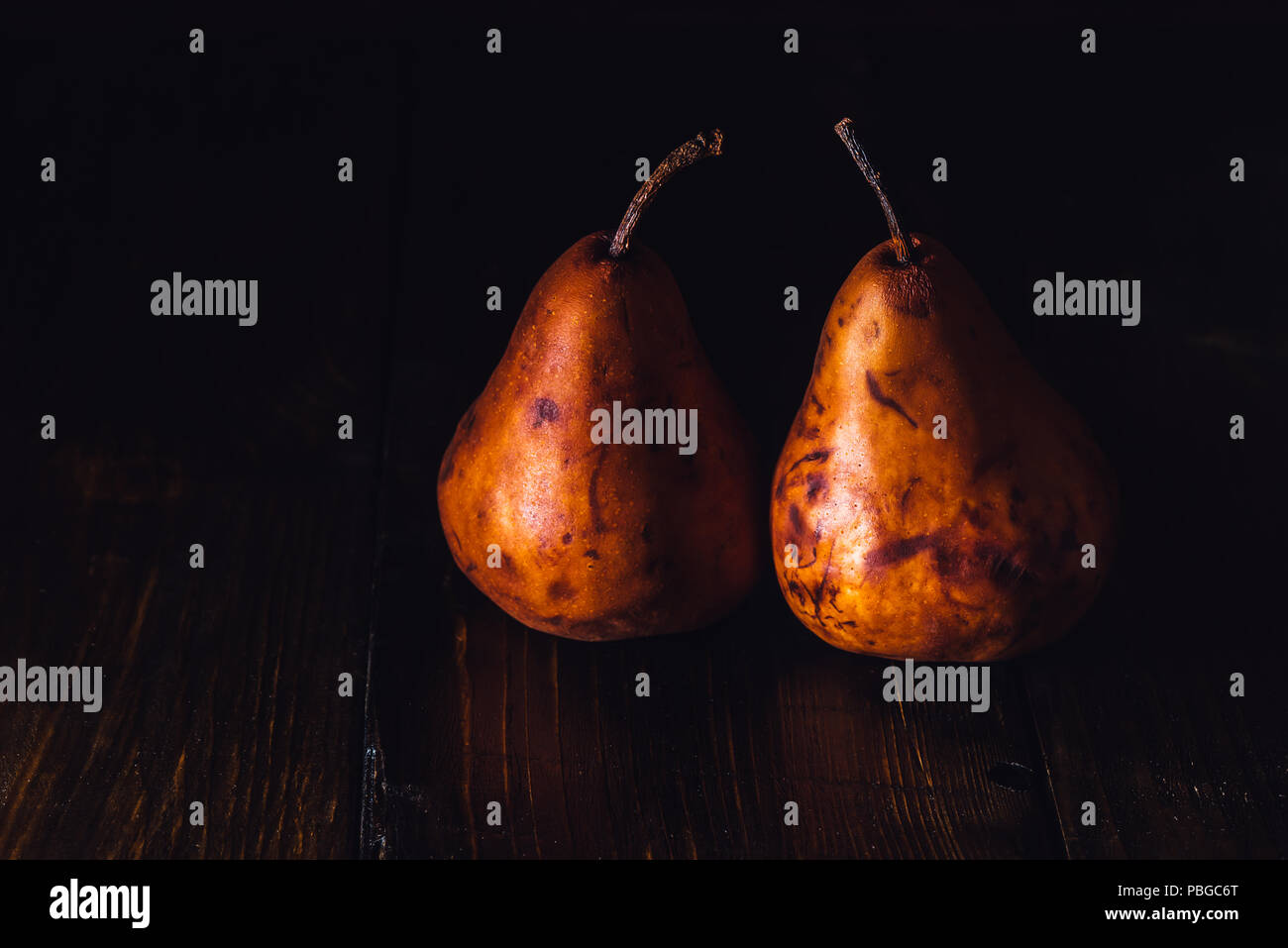 Two Golden Pears on Dark Wooden Table Stock Photo