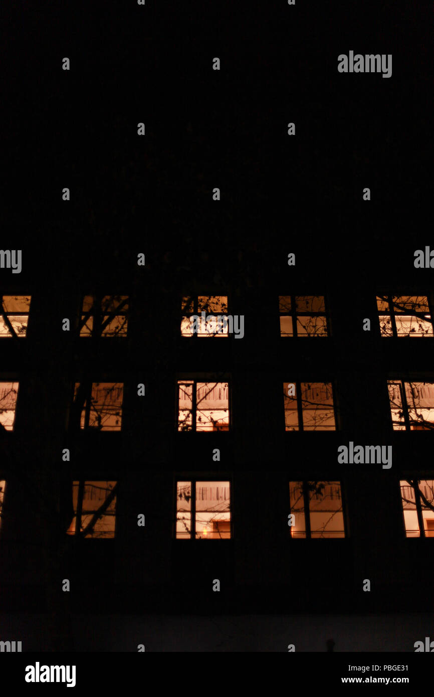 illuminated windows on an apartment building at night Stock Photo