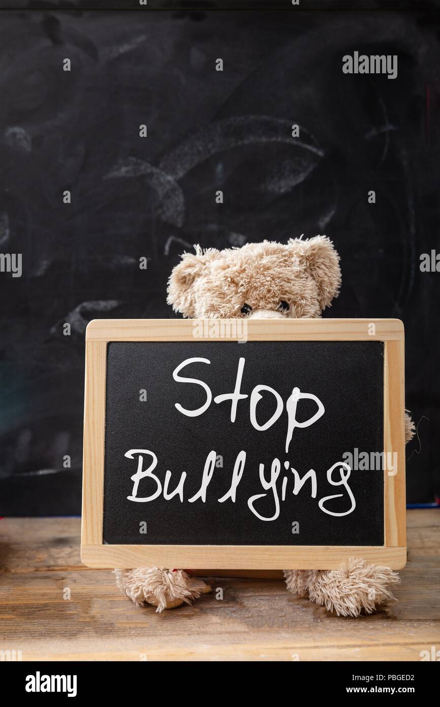 Bullying at school. Teddy bear behind a blackboard, stop bullying text on the blackboard Stock Photo