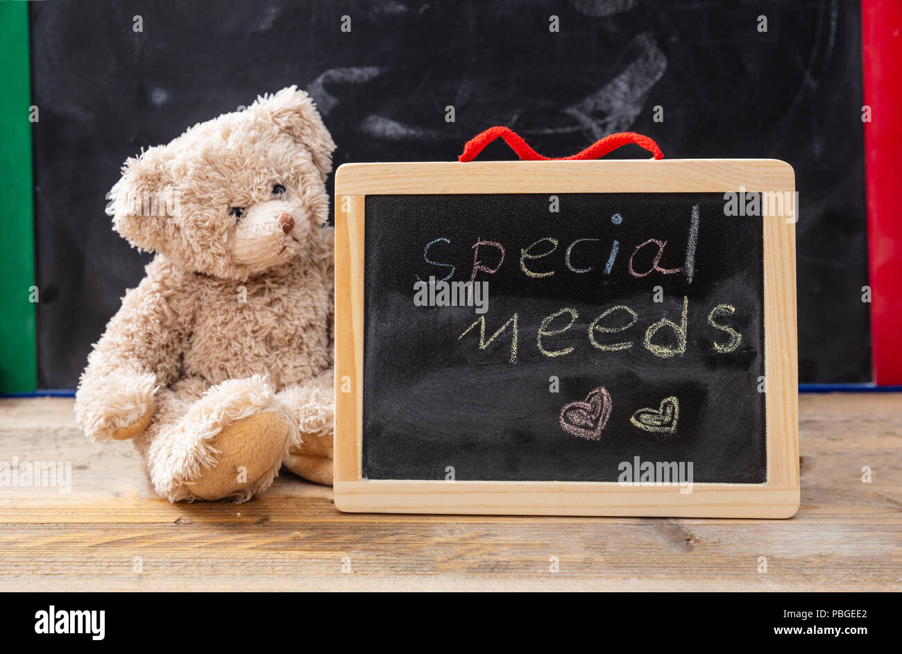 Special needs at school. Teddy bear hiding behind a blackboard. Special needs text drawing on the blackboard Stock Photo
