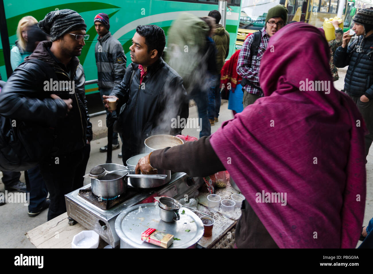 Passengers waiting at a street food stall to take the morning bus from Kathmandu to Pokhara, Nepal Stock Photo