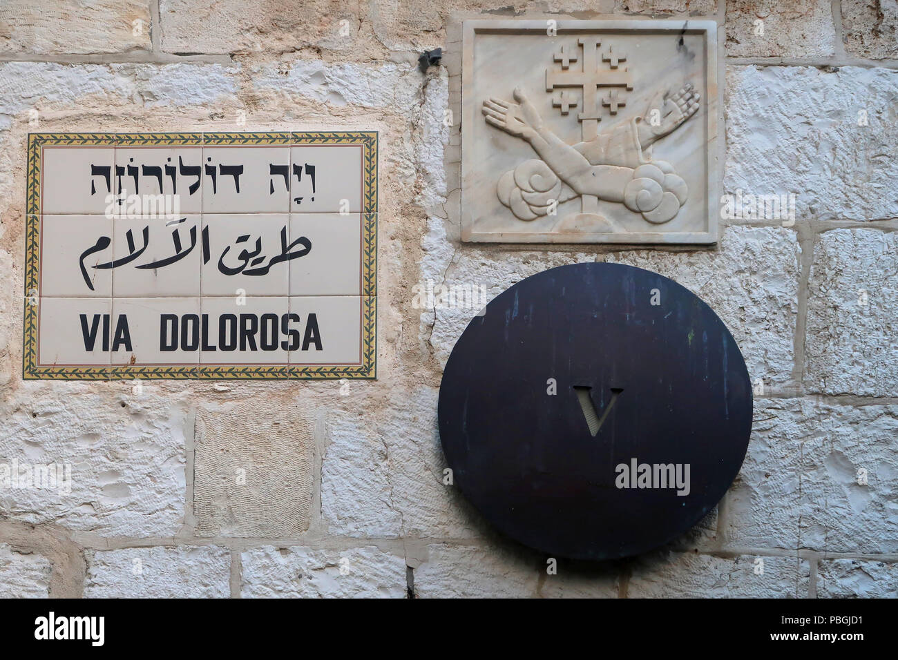 Sign on ceramic tiles in English Hebrew and Arabic at the Chapel of Simon of Cyrene the 5th station of the cross along in Via Dolorosa street believed to be the path that Jesus walked on the way to his crucifixion in the Old City. East Jerusalem, Israel Stock Photo
