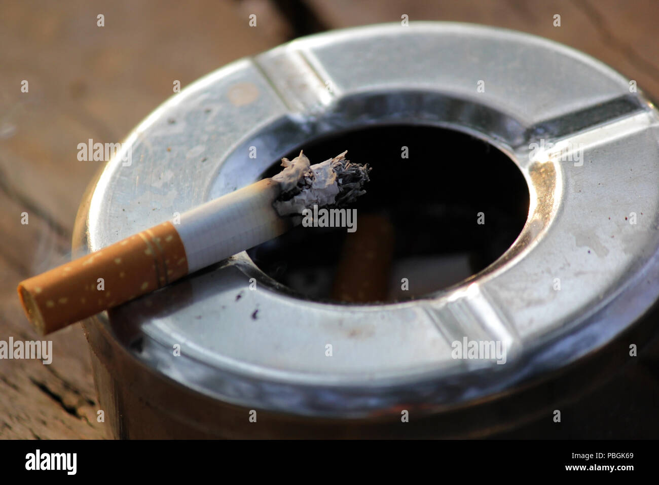 closeup of smoked cigarette in stainless ashtray Stock Photo