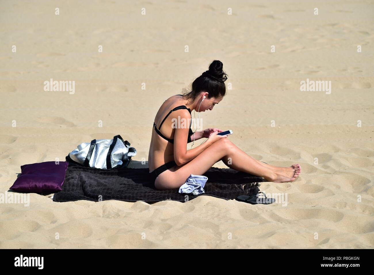 Chicago, Illinois, USA.A woman accessing her cell phone wil relaxing at Hollywood Beach, also known as Kathy Osterman Beach. Stock Photo