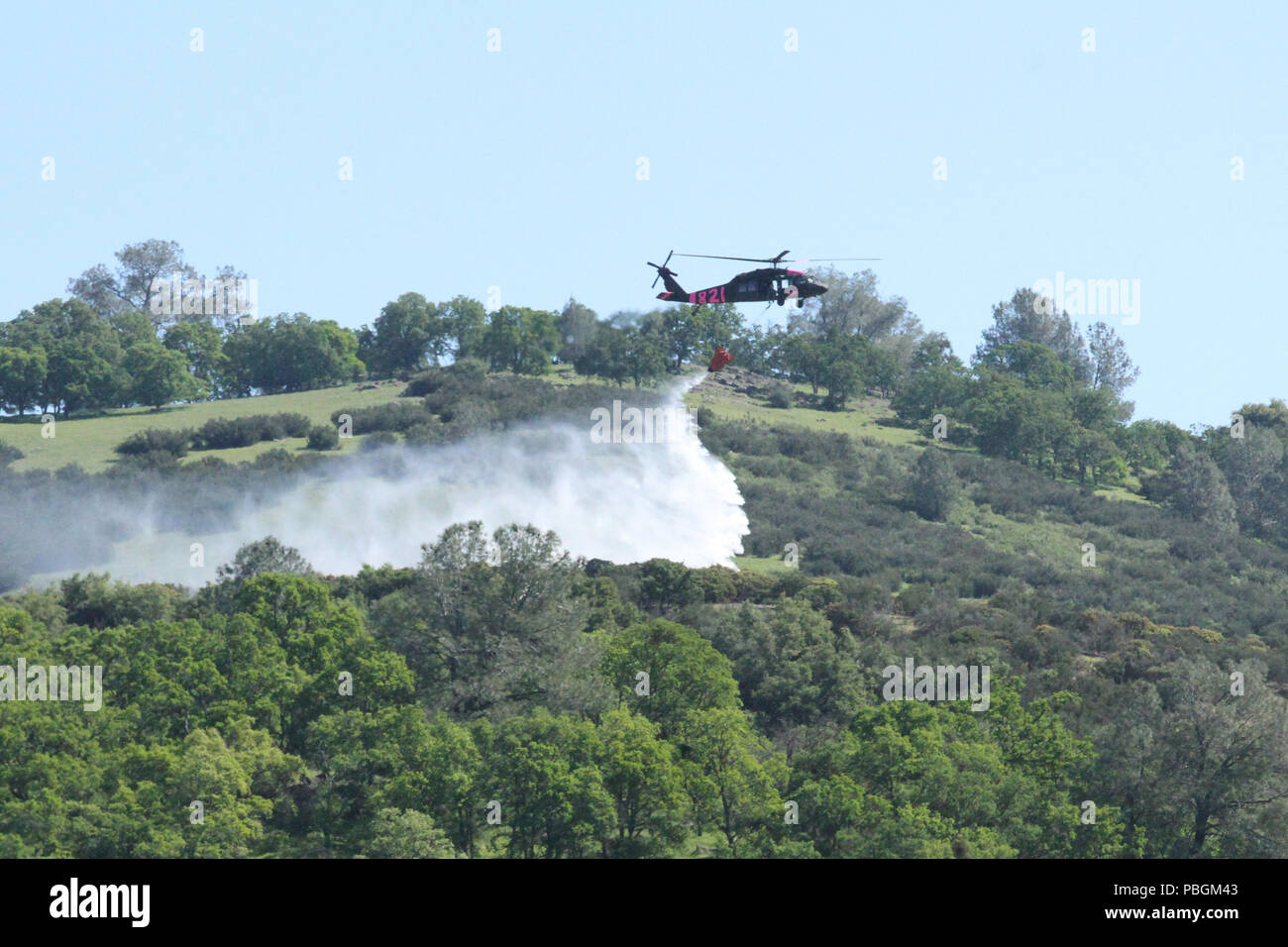 A UH-60 Black Hawk helicopter of the California Army National Guard drops water over a simulated wildfire April 14, 2018, near Lake Pardee in Ione, California, during an annual exercise between Cal Guard and the California Department of Forestry and Fire Protection (CAL FIRE). The organizations annually prep for wildfires in April, as the summer months lead to California’s toughest fire-fighting season. (U.S. Army National Guard photo by Staff Sgt. Eddie Siguenza) Stock Photo
