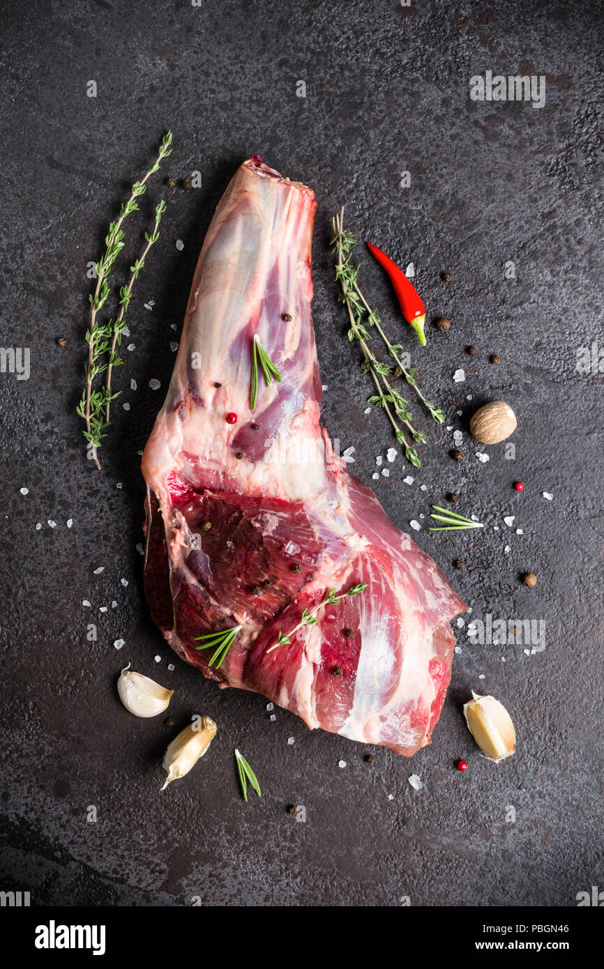 Raw fresh Lamb Meat shank and seasonings on black stone background. Stock Photo