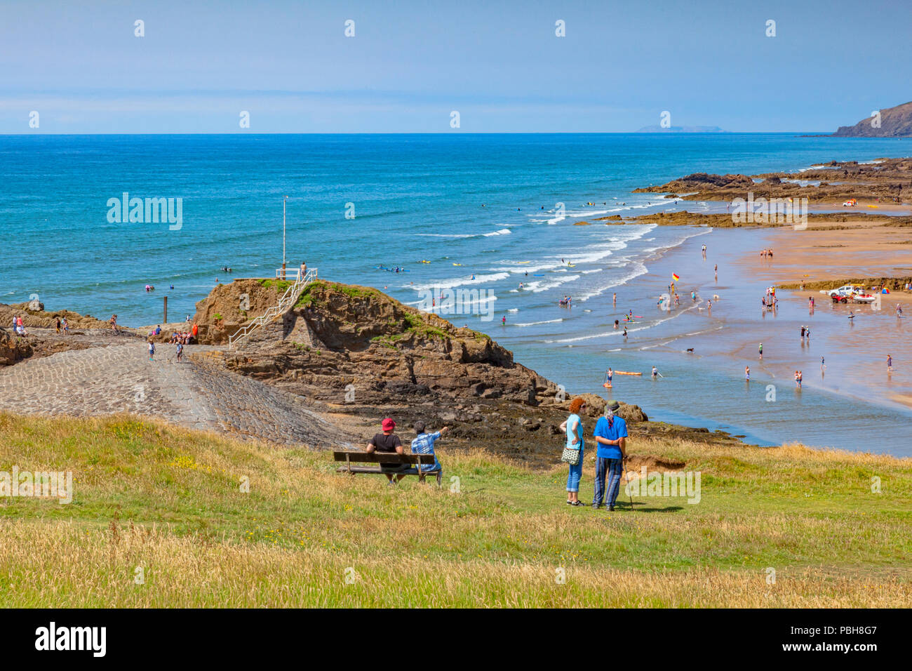 6 July 2018: Bude, Cornwall, UK - Tourists on Compass Hill looking down over busy Summerleaze Beach during the summer heatwave, as people cool off in  Stock Photo