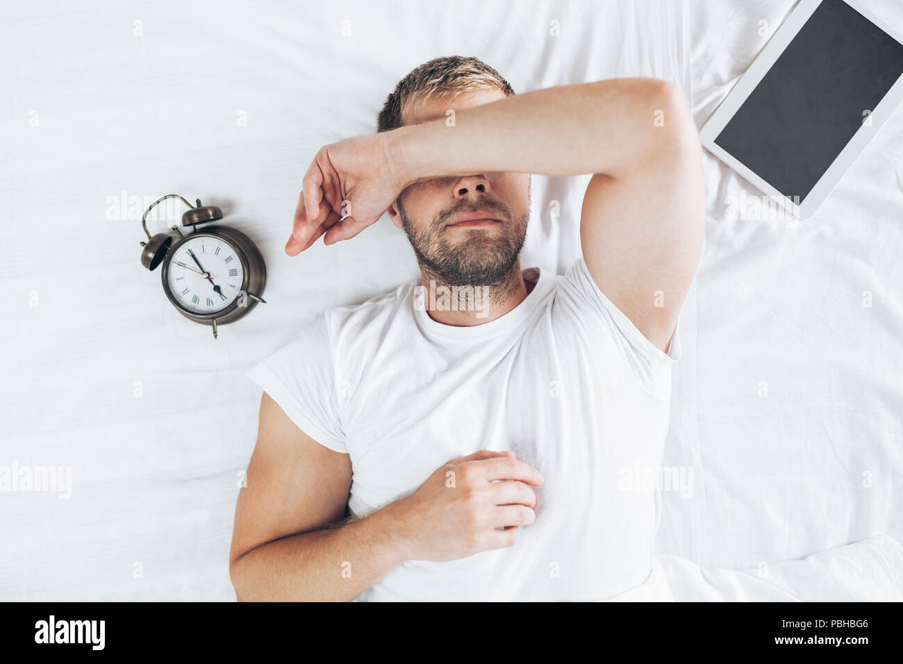 Tired man sleeping on bed after using his digital tablet Stock Photo