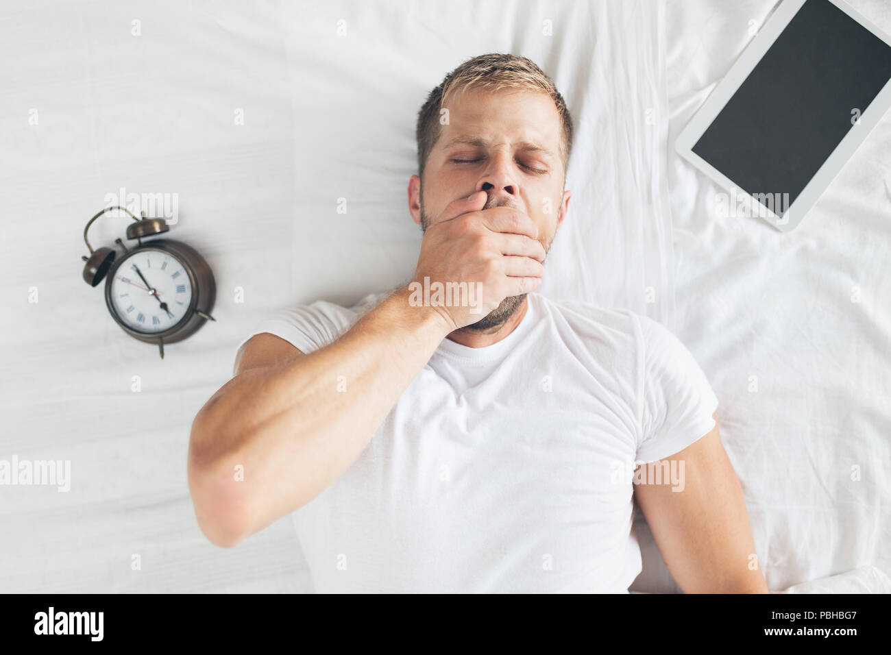 Tired man sleeping on bed after using his digital tablet Stock Photo