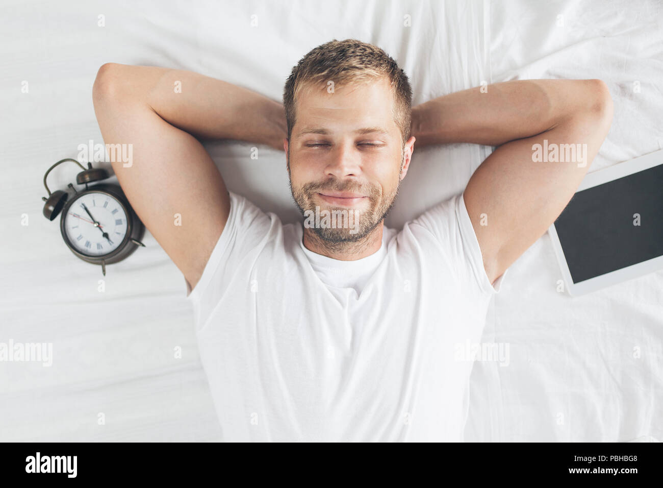Tired man sleeping on bed after using his digital tablet Stock Photo