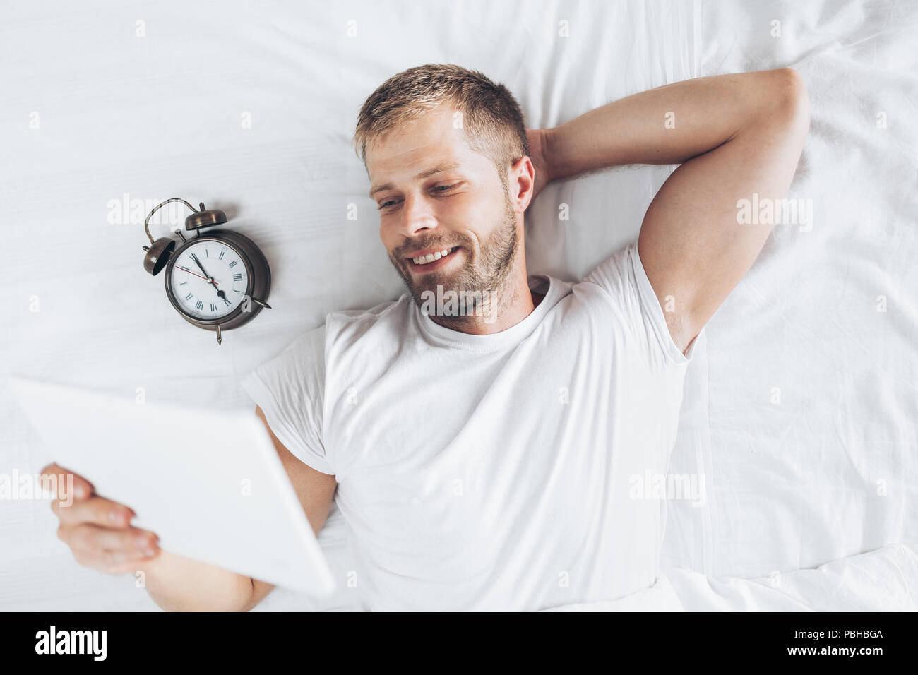 Handsome man using a digital tablet in bed at home Stock Photo