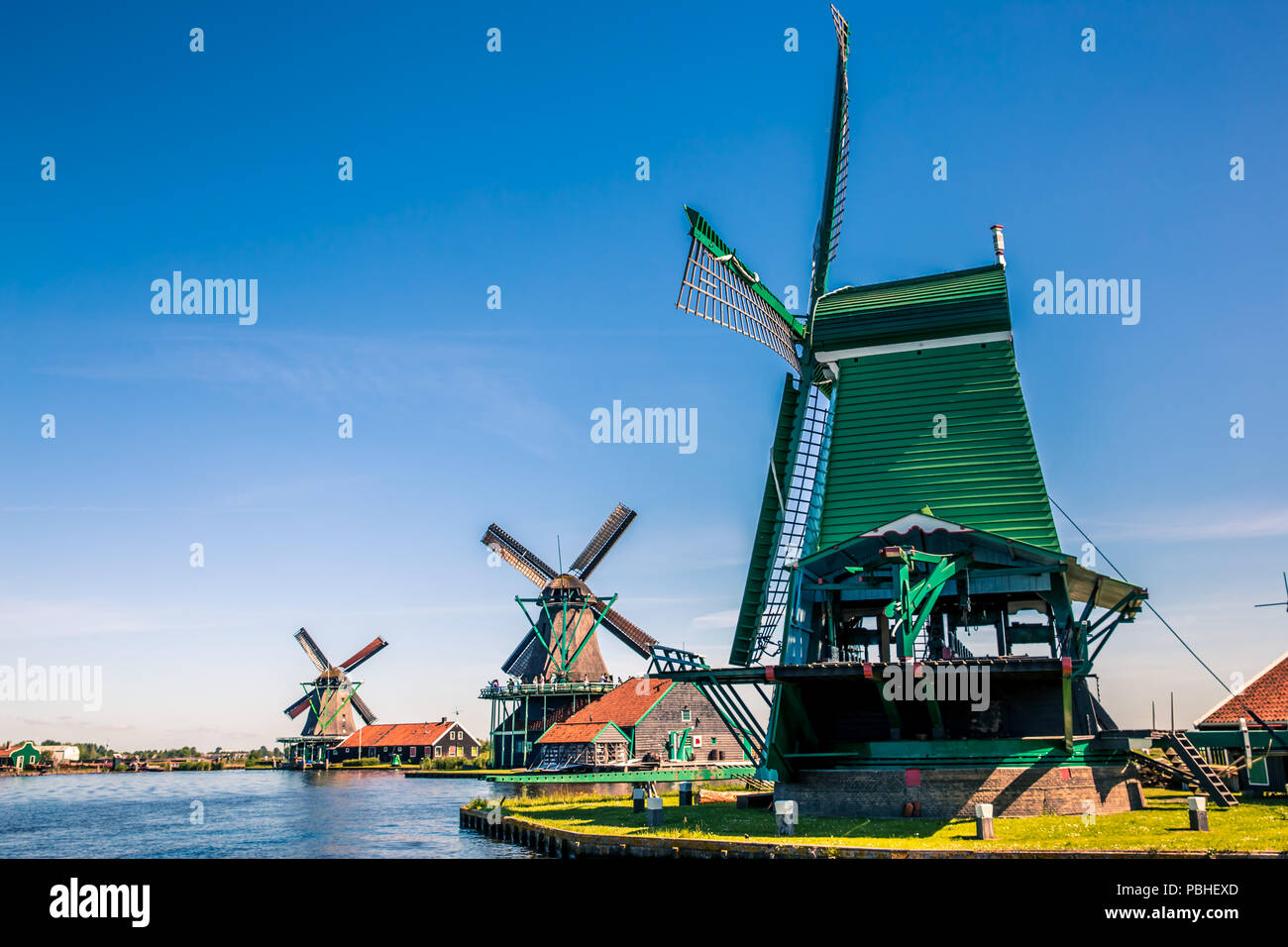 Traditional dutch windmills located by the river Zaan, in Zaanse Schans, Netherlands. Stock Photo