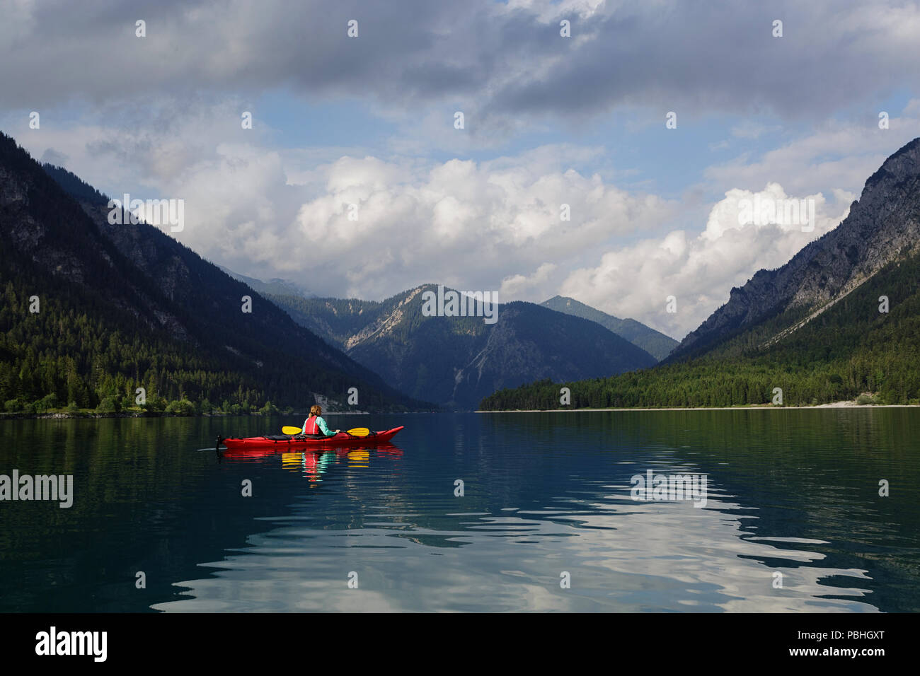 Woman kayaking in a red kayak on lake Plansee, Austria Stock Photo