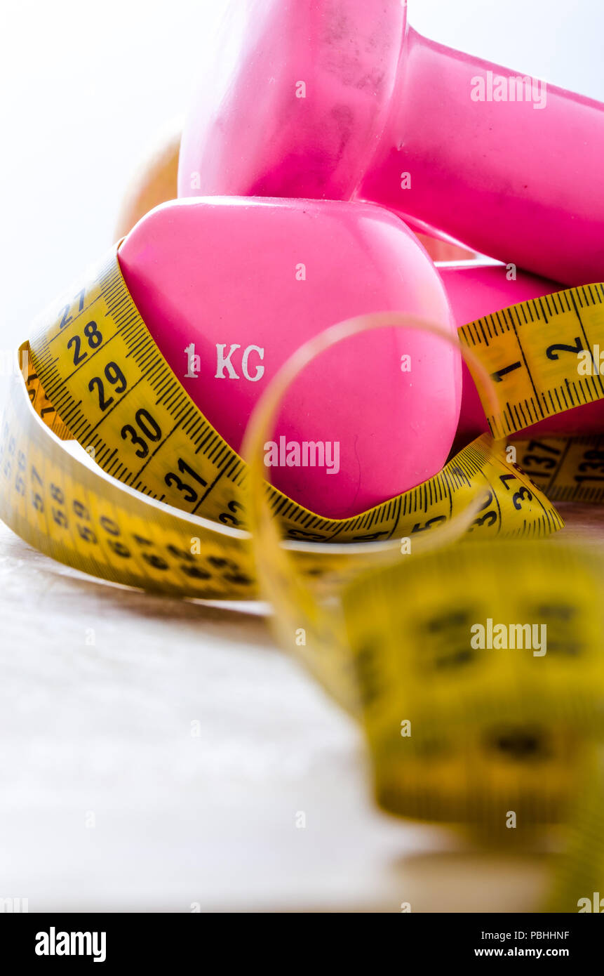 still life and close up with apple, pink weight, yellow tape measure. fitness and lifestyle concepts. Stock Photo