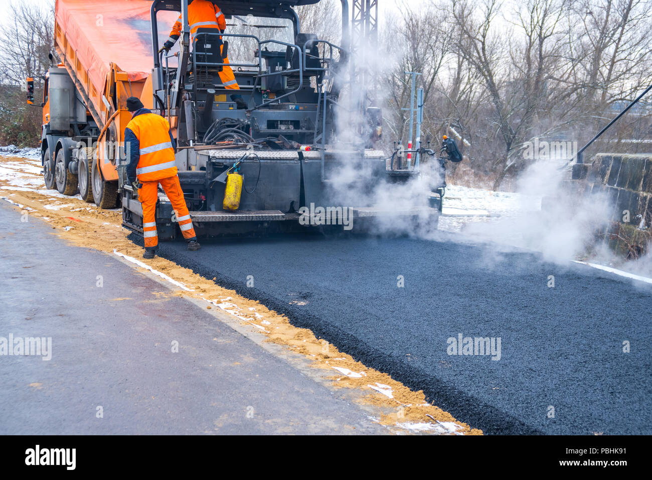 Worker operating asphalt paver machine during road construction and
