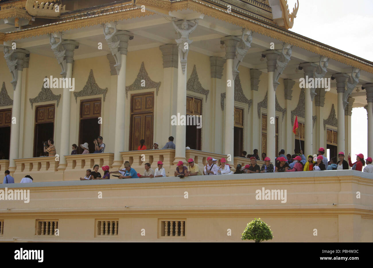 Lots of Tourists Wearing Red Hats on Balcony Looking Out, Royal Palace, Phnom Penh, Cambodia Stock Photo