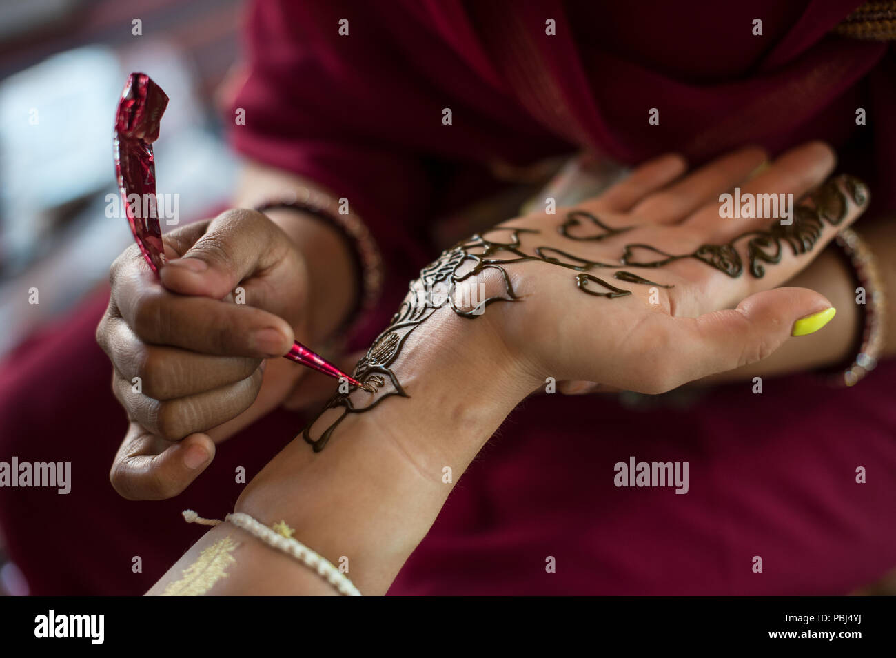 Indian painter to paint the hand of a tourist with henné colour, Jaipur, Rajasthan, India Stock Photo