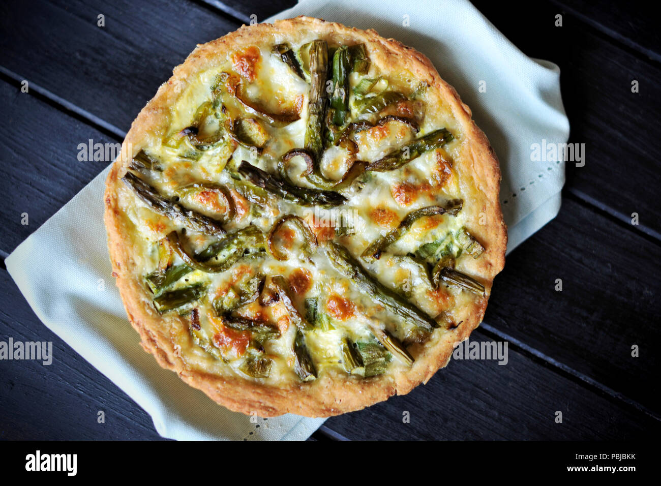 open pie with asparagus cheese and eggs. On black, decorated with ...