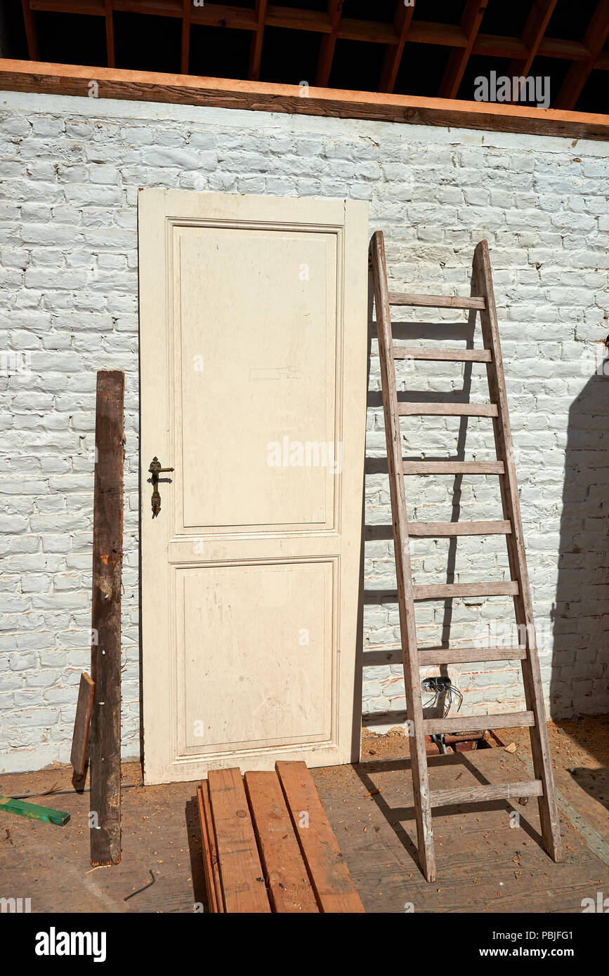 Wooden door unmounting against brick wall and ladder. Before renovate Stock Photo