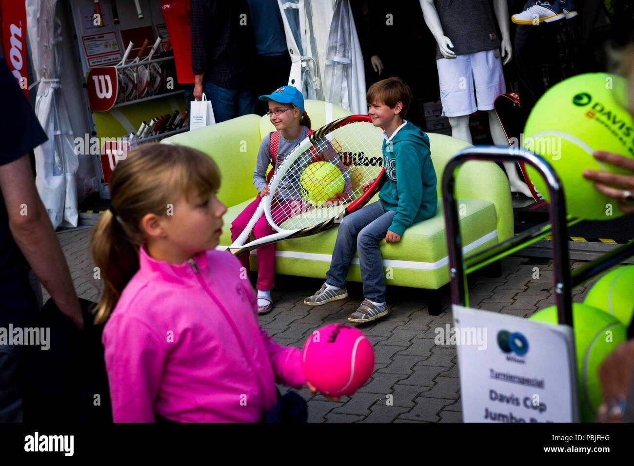 Young tennis fans pose for a photograph on a sofa with an oversized tennis racket and ball at the Gerry Weber Open in Halle (Westfalen), Germany Stock Photo