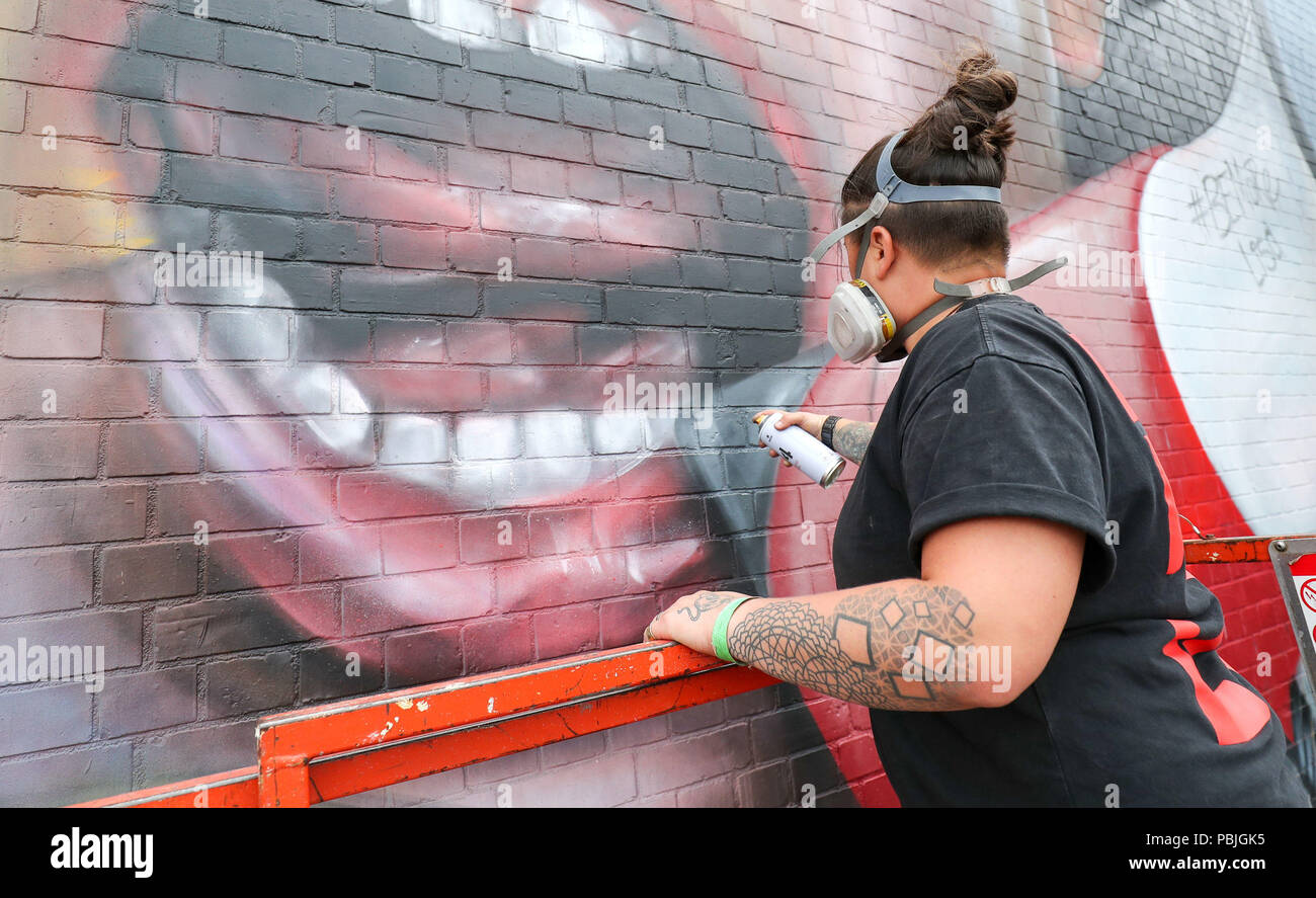 Hayley Garner of Nomad Clan, spray paints a mural on the side of the old Tobacco Factory on North Street in Bristol, during the Upfest 2018 festival in Bristol, Europe's largest Street Art & Graffiti festival. Stock Photo