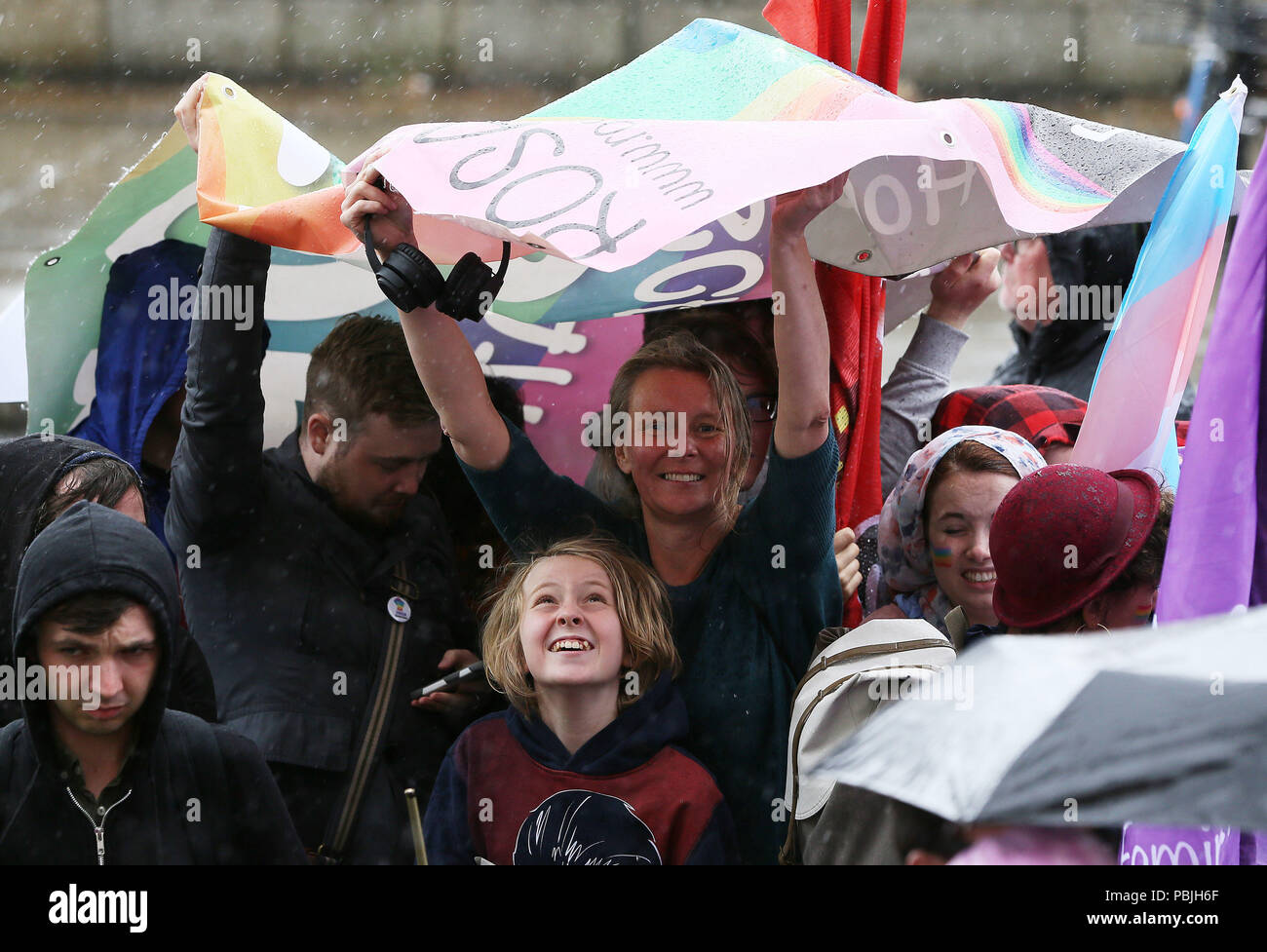 People use a banner to shelter from the rain during a Trans Pride March in Dublin's city centre. Stock Photo