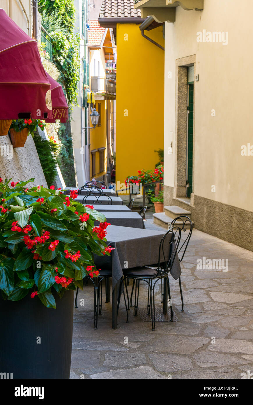 tables, chairs and flowers in the small alley of Varenna, Italy Stock Photo