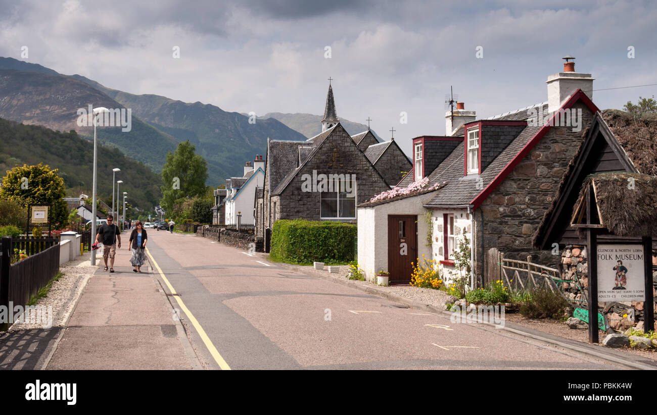 Glencoe, Scotland, UK - May 22, 2010: Tourists walk past houses and the village church of Glencoe village in the West Highlands of Scotland, with Bein Stock Photo