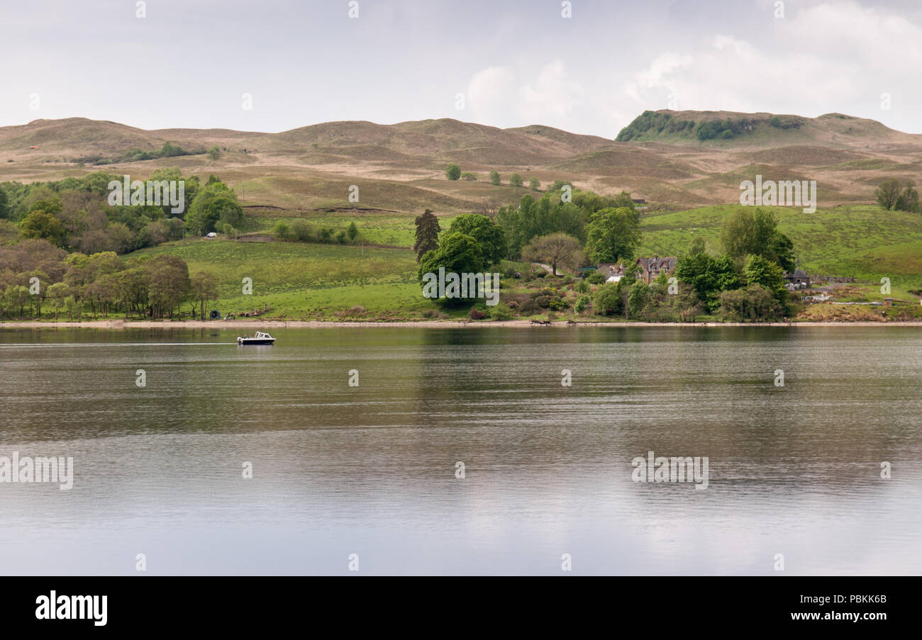 A boat cruises on Loch Awe lake under Creag Thulach Hill in Argyll in the West Highlands of Scotland. Stock Photo