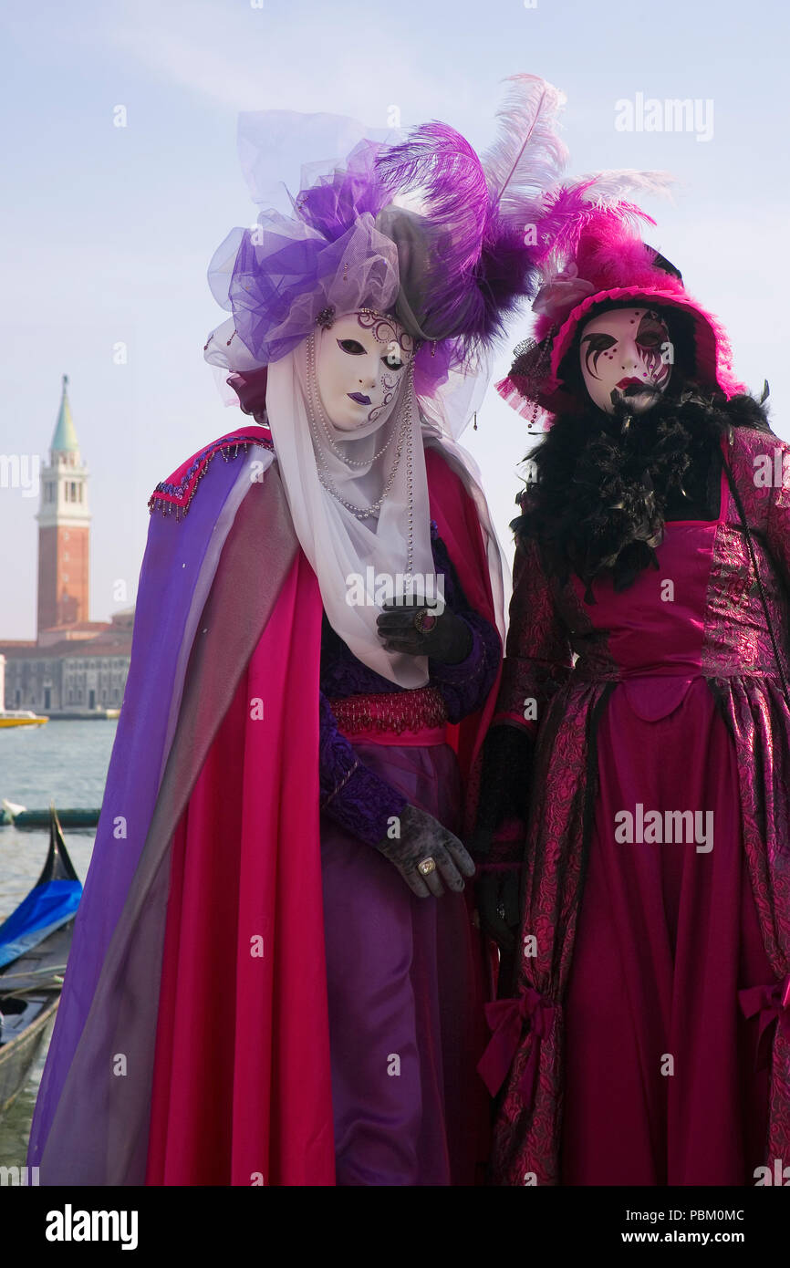 Riva degli Schiavoni, San Marco, Venice, Italy: masked revellers pose in front of the Basin of St. Mark, with San Giorgio Maggiore in the background Stock Photo