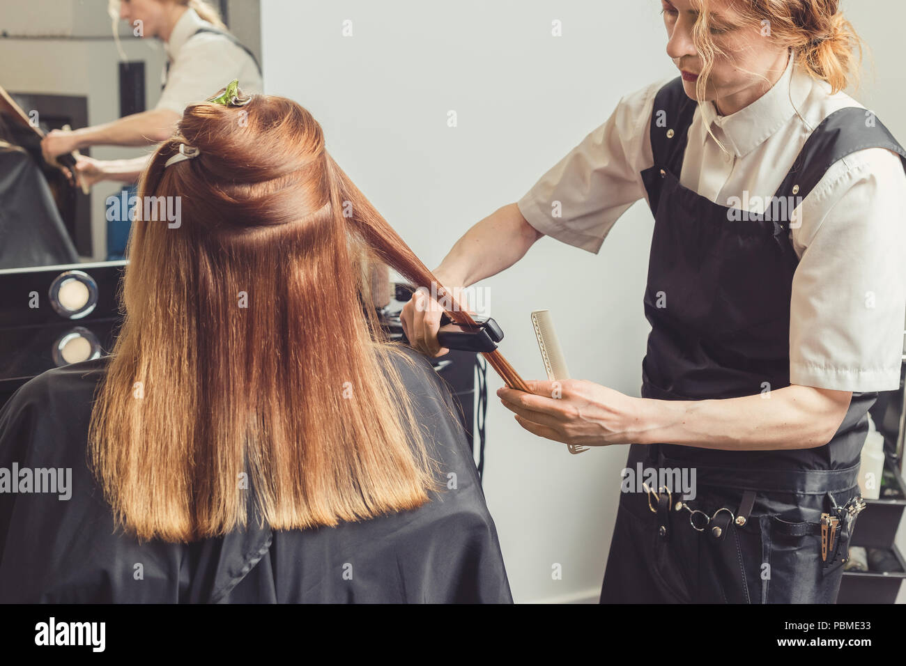 Hair straightening at beauty salon. Hairdresser making a hairstyle for client with a hair iron Stock Photo Alamy