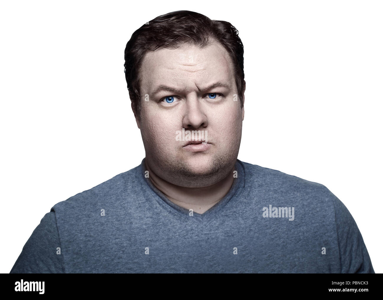 Close-up portrait of white Caucasian big fat stout man with blue eyes looking directly in camera in studio on light background, sceptical suspicious e Stock Photo