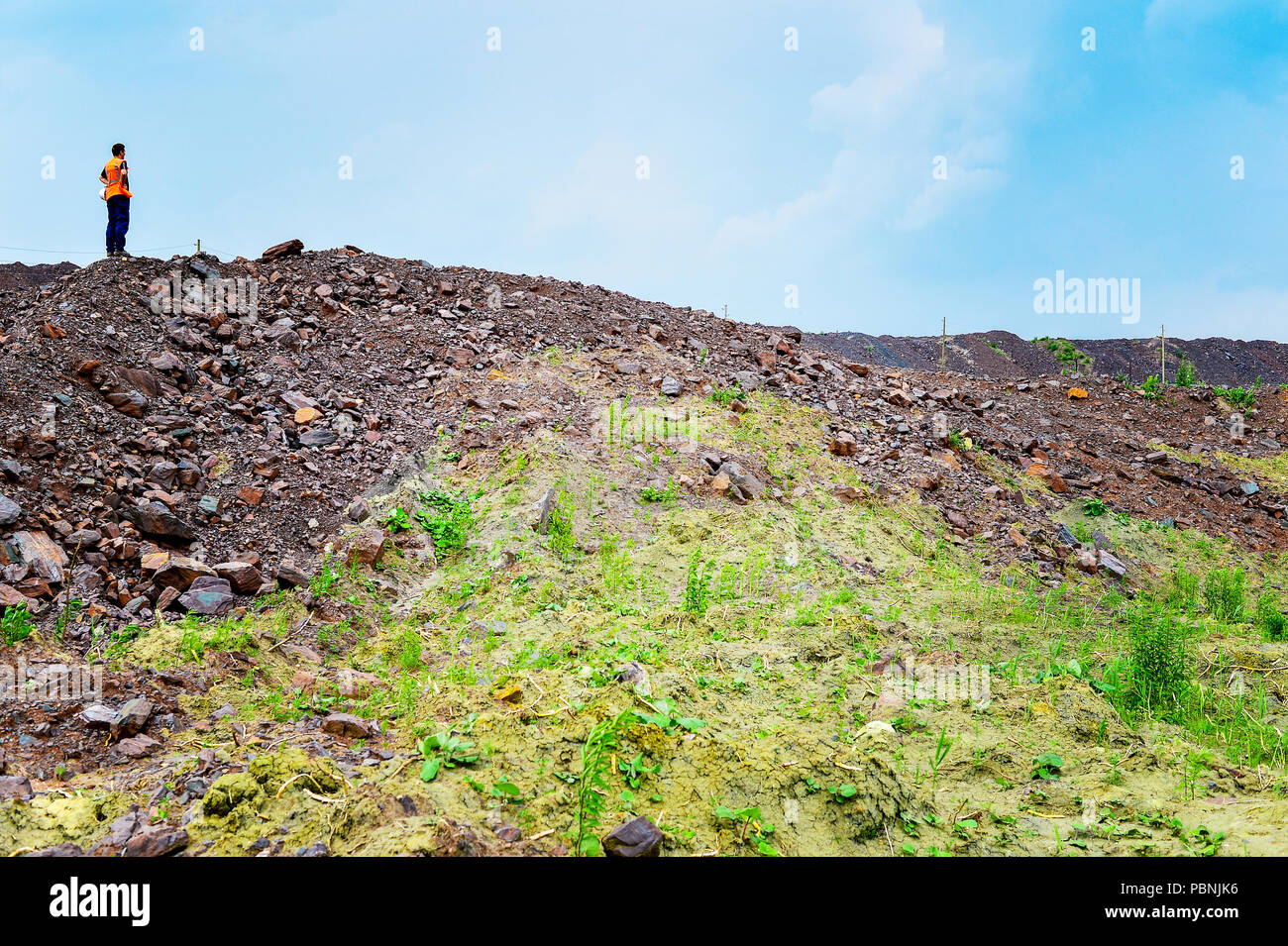 The worker is at the top of the rock heap in his quarry. Stock Photo